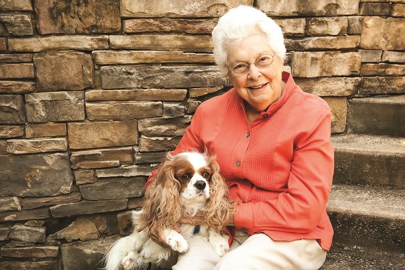 An elderly woman sitting outdoors with her dog.