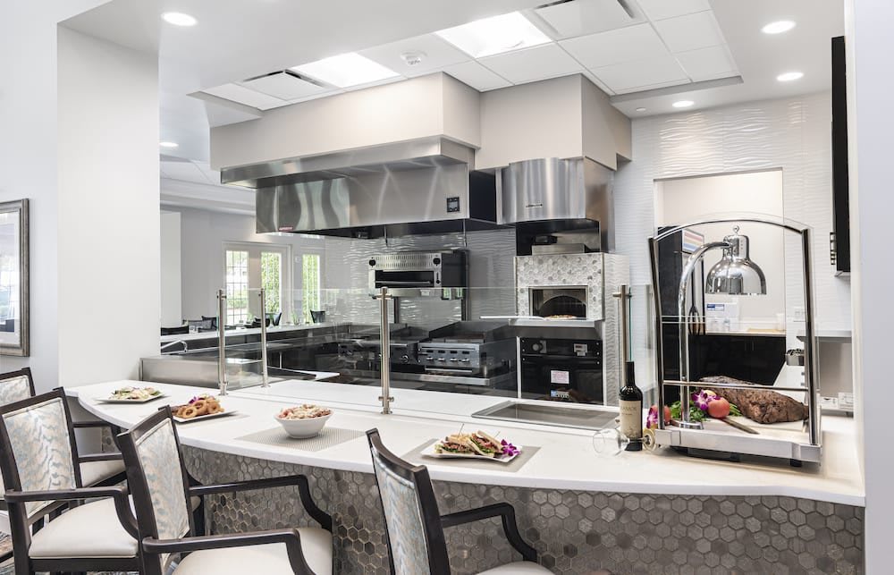 A modern kitchen with a sleek design, featuring a spacious cooking area and countertop seating.