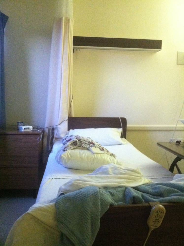 A hospital room with an unoccupied bed and medical equipment.