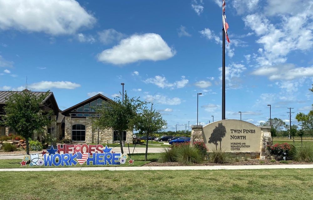 Exterior view of a library with a sign, American flag, and colorful decoration under a blue sky.