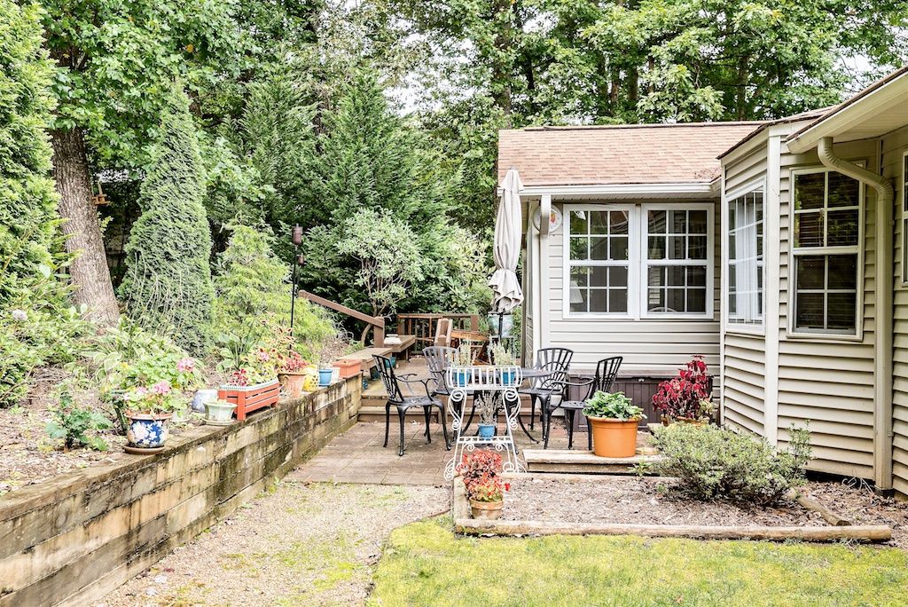 A cozy patio area with outdoor seating, surrounded by lush greenery and potted plants.