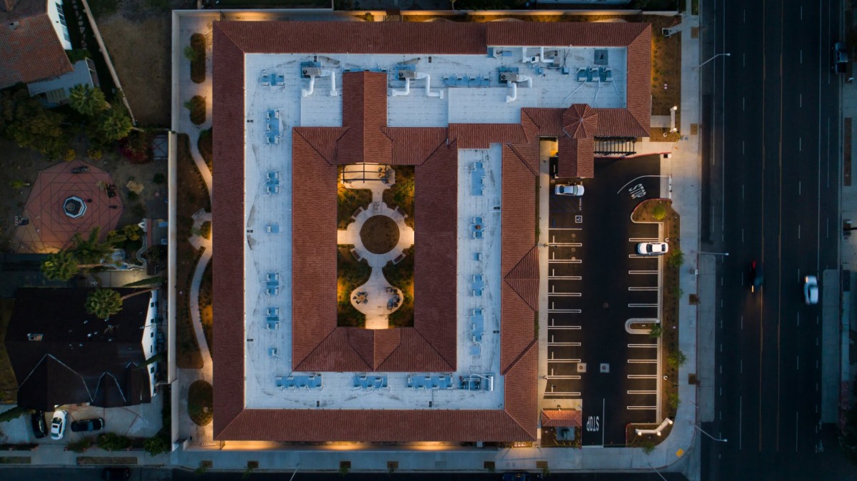 Aerial view of a building with a central courtyard and adjacent parking lot.