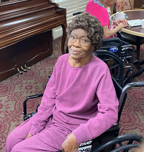 An elderly woman in a wheelchair smiling warmly, enjoying her time at a care facility.