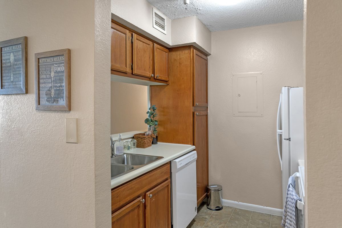 A compact kitchen area featuring wooden cabinets, a sink, and modern appliances.