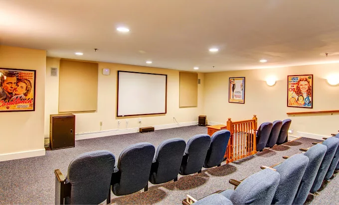 A cozy home theater setup with several rows of comfortable seating and a large screen for movie viewing.