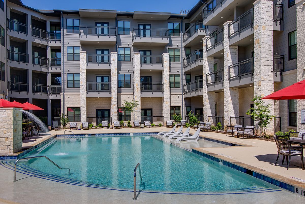 A modern apartment complex with a central swimming pool and balconies.