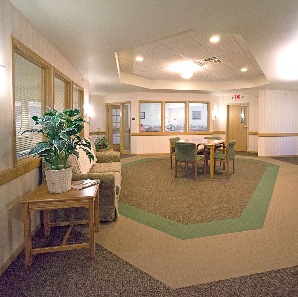 A cozy lobby area with tables, chairs, and a potted plant.