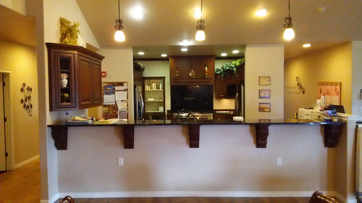 A modern kitchen area featuring a countertop with pendant lights and wooden cabinetry.