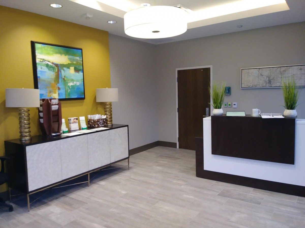 A modern and welcoming office reception area featuring a coffee station and decorative art.