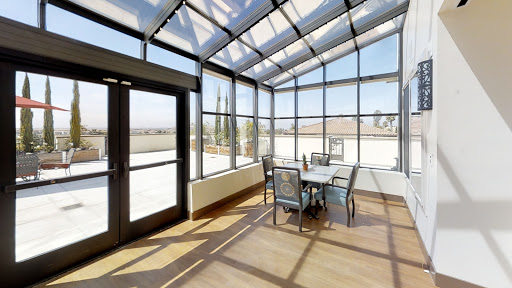 A bright and modern sunroom featuring glass walls and a cozy seating area, perfect for enjoying natural light.