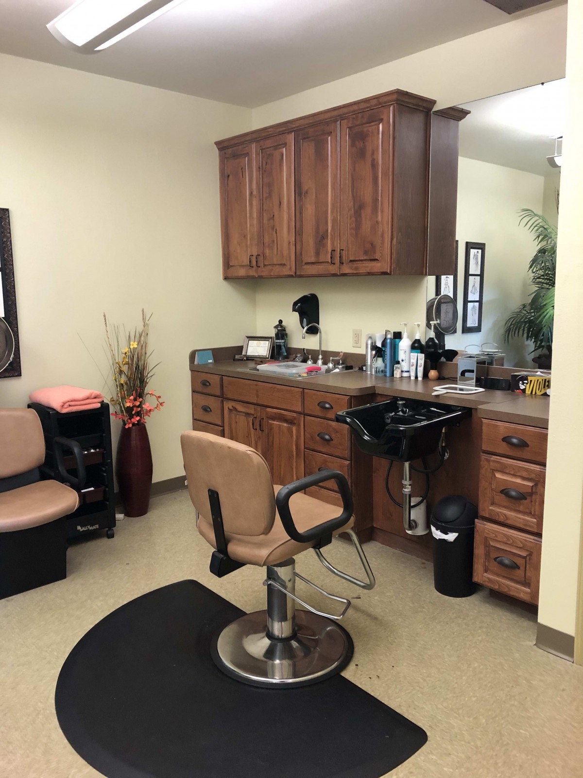 A cozy salon setup with a styling chair, mirror, and wooden cabinetry.