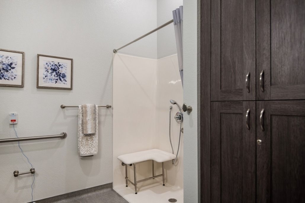 Modern bathroom with an accessible shower featuring grab bars and a shower chair.