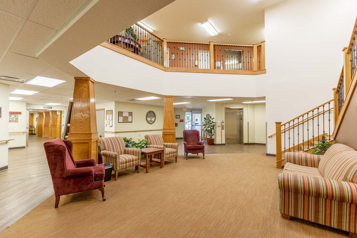 A spacious and warmly decorated lobby area with comfortable seating and a staircase leading to an upper level.