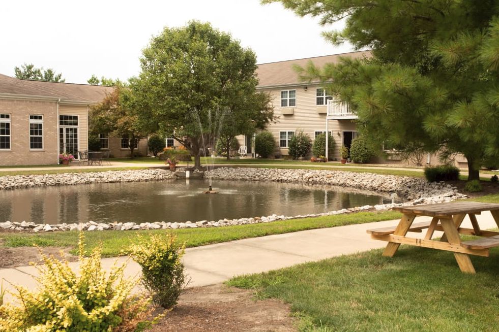 A serene courtyard with a pond surrounded by trees and buildings.