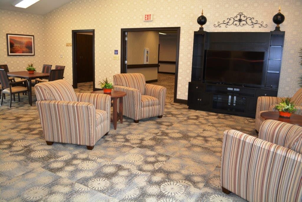 A cozy lobby area with striped armchairs, a patterned carpet, and a large television.