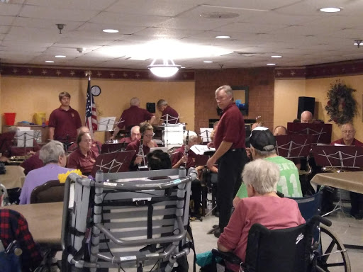 A community musical performance for residents in an assisted living facility, featuring a small band and an engaged audience.