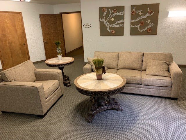 A cozy waiting room with a sofa, chair, and decorative tables.