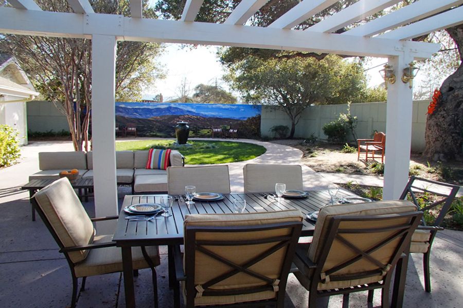 A beautiful backyard patio with a pergola, featuring a dining area and well-maintained garden.