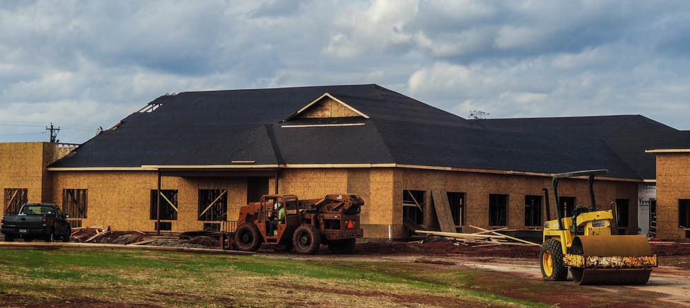 A house under construction with a tractor parked in front.