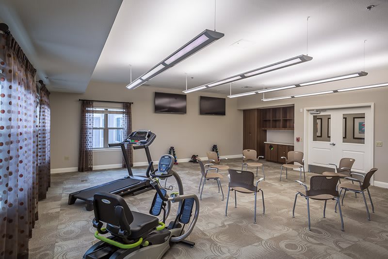 A well-lit fitness center with exercise equipment and seating.
