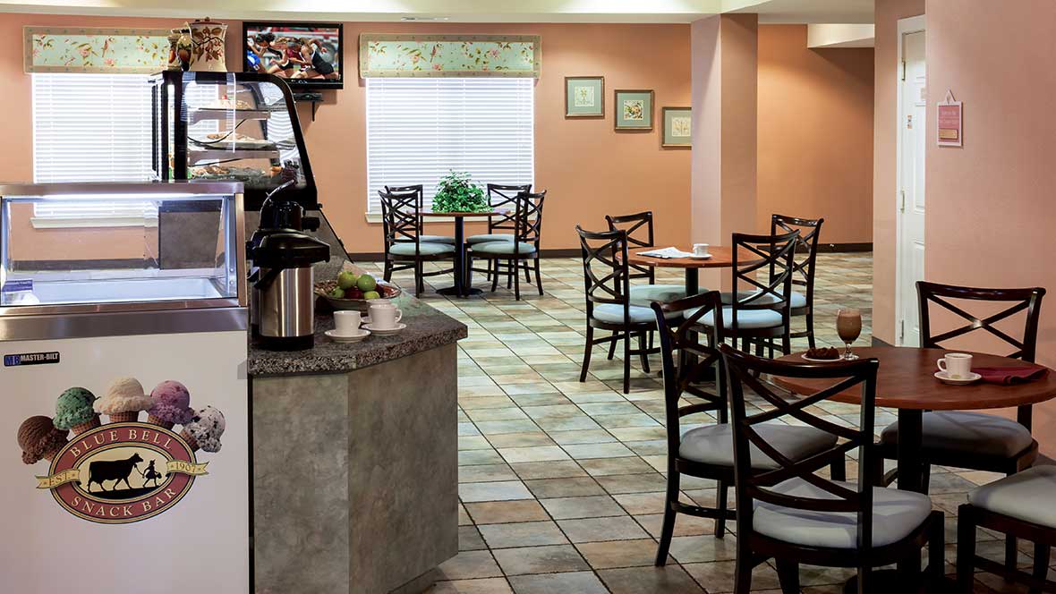 An empty cafe with neatly arranged tables and chairs, featuring a coffee station.