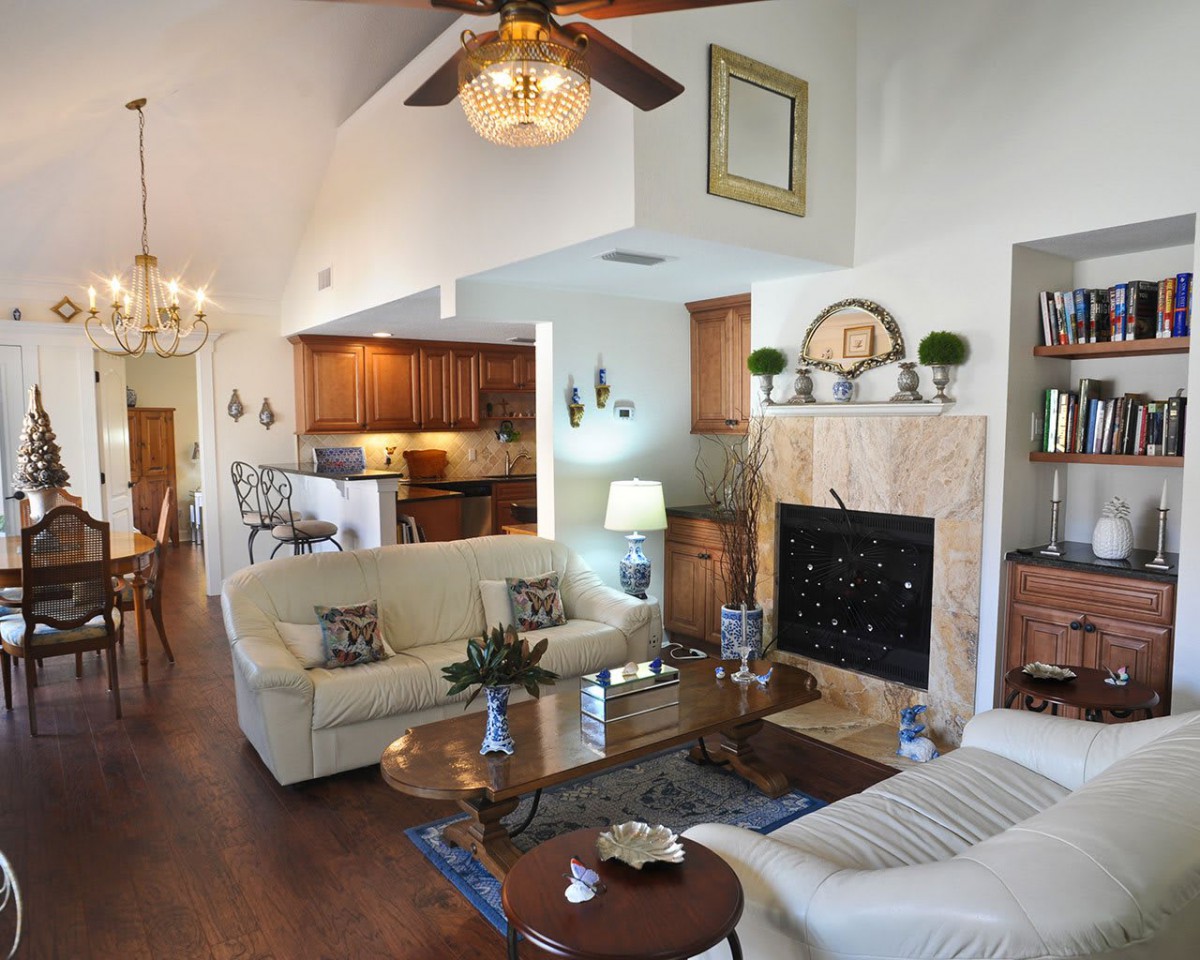 A cozy living room with a fireplace, comfortable sofas, and an open layout connecting to the kitchen and dining area.