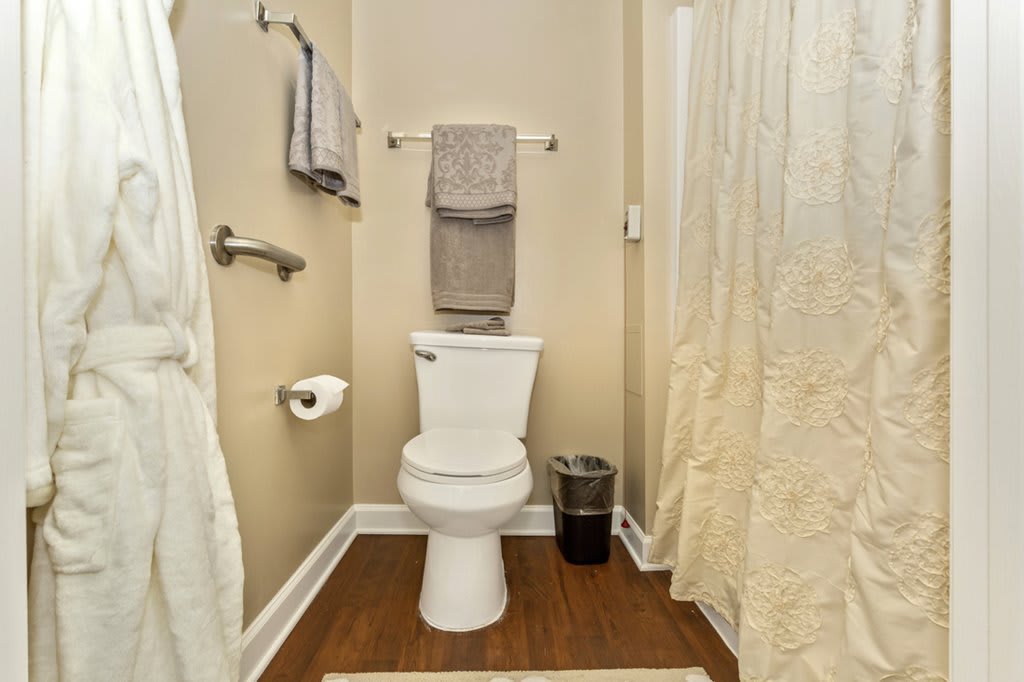A modern bathroom with a toilet, neatly arranged towels, and a shower area.