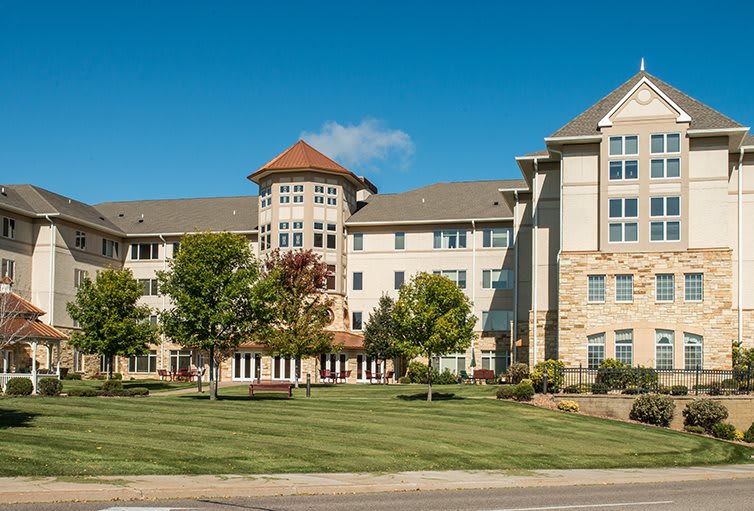 A large residential building surrounded by trees and a well-maintained lawn.