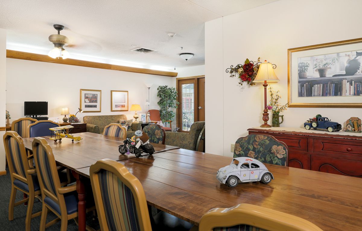 A cozy living and dining area featuring a wooden dining table adorned with toy cars, surrounded by comfortable seating and decorative elements.