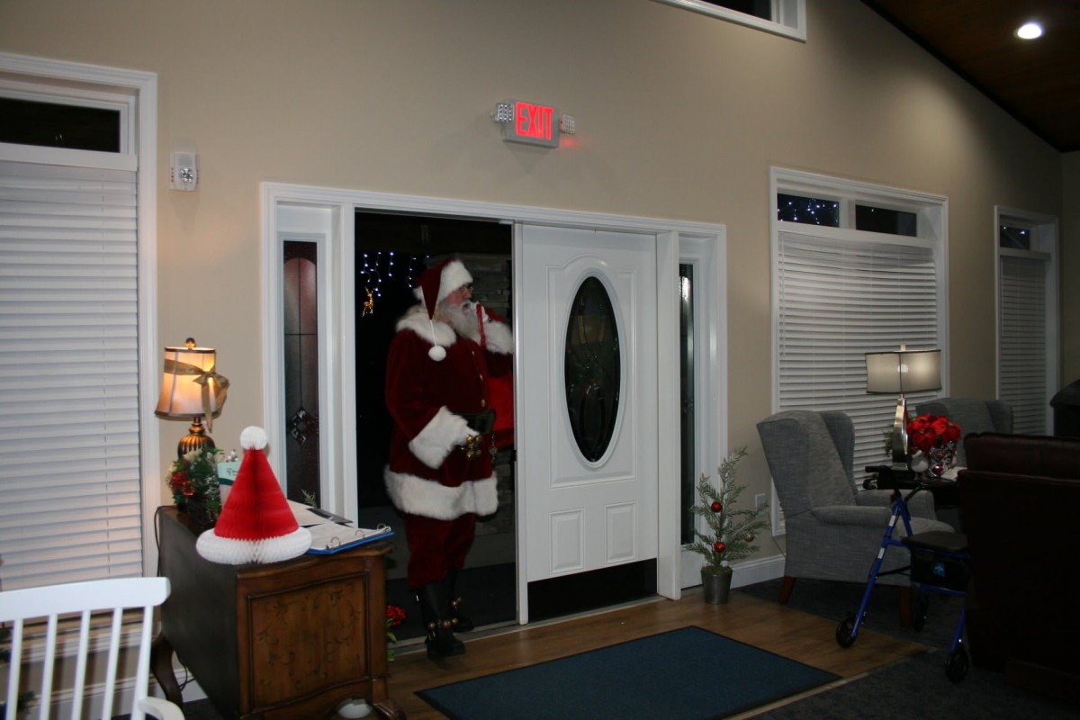 Santa Claus entering a festive room decorated for Christmas.