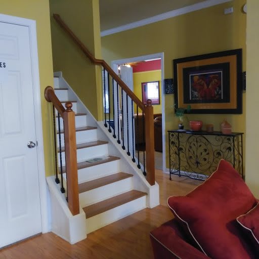 A cozy living room with a wooden staircase and colorful decor.