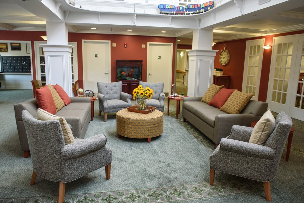 A cozy living room with several sofas and chairs arranged around a central coffee table, featuring warm lighting and tasteful decor.