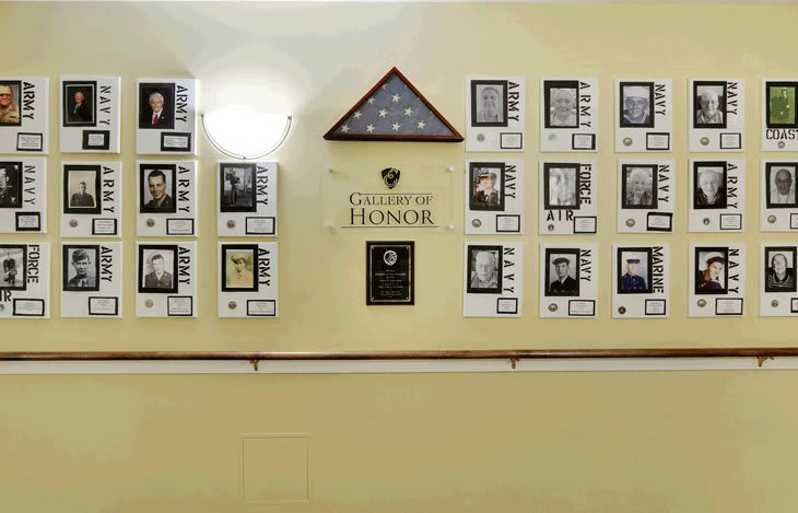 A wall display titled 'Wall of Honor' featuring plaques and photographs honoring individuals, accompanied by a folded American flag.