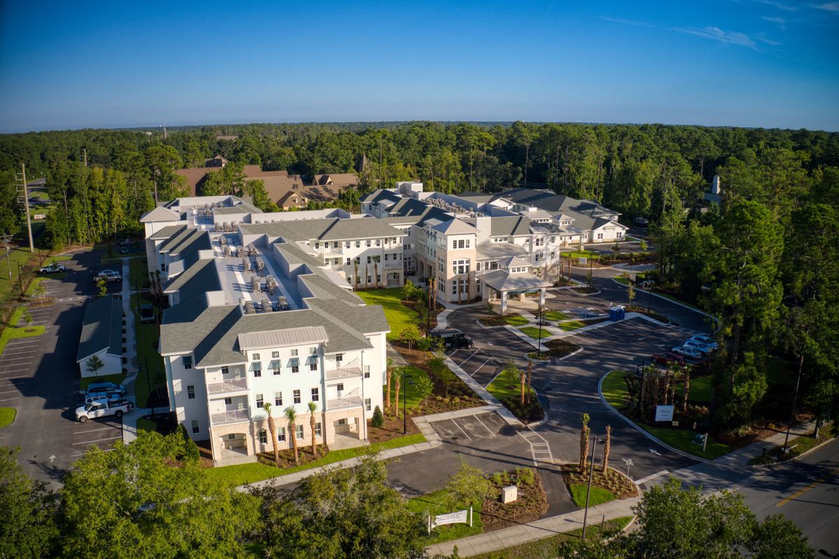 Aerial view of a residential complex surrounded by trees and clear blue skies.