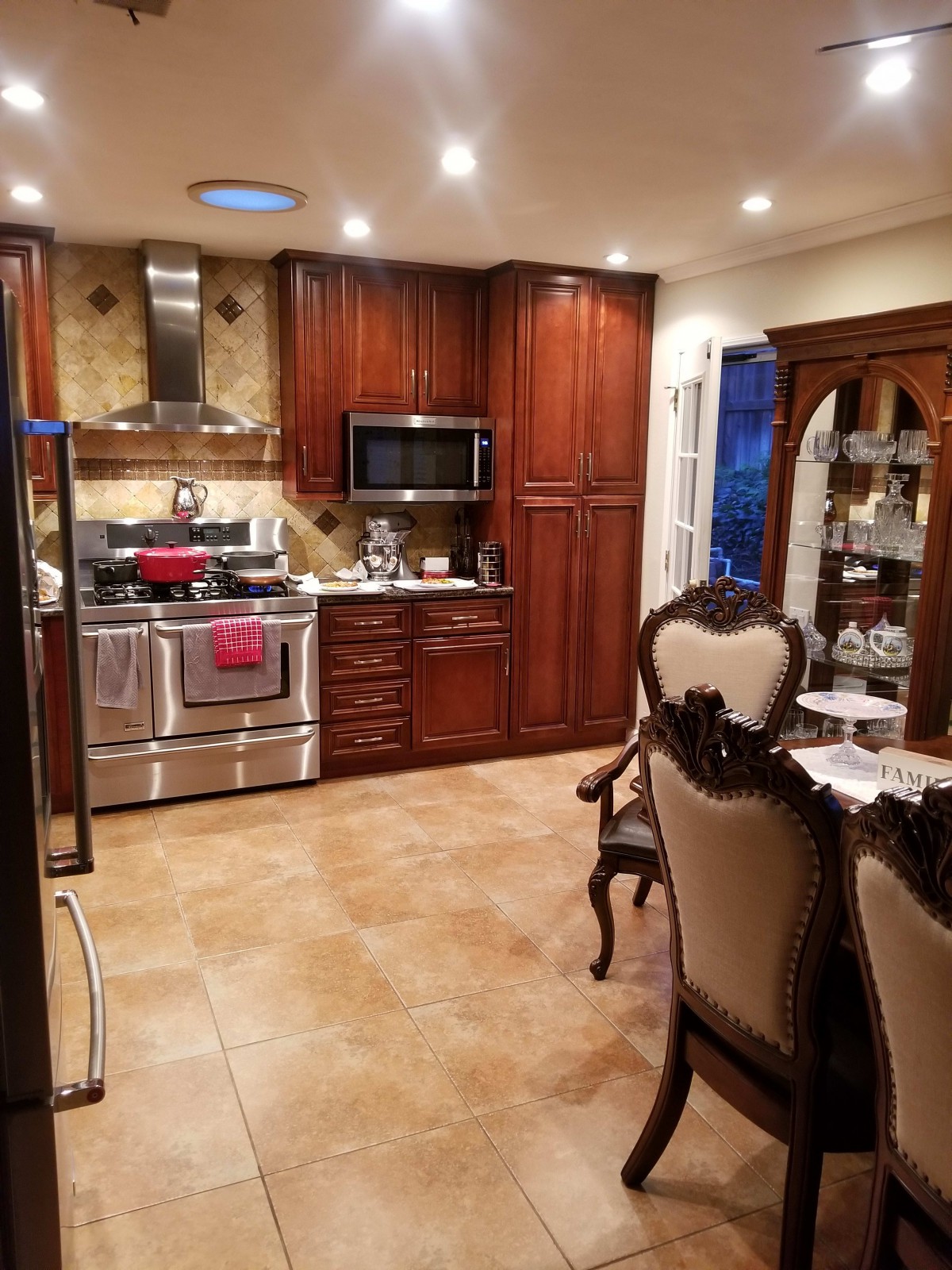 A stylish modern kitchen with wooden cabinets, stainless steel appliances, and an adjacent dining area.