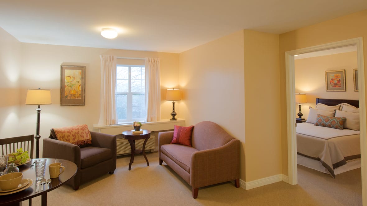 A cozy living room with two sofas, a lamp, and a window providing natural light.