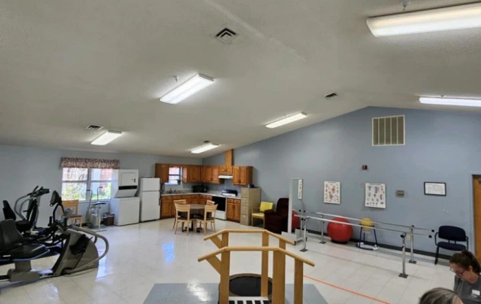 A multi-purpose rehabilitation room with kitchen facilities and therapy equipment.