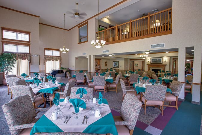 A spacious dining room with elegantly set tables and chandeliers.