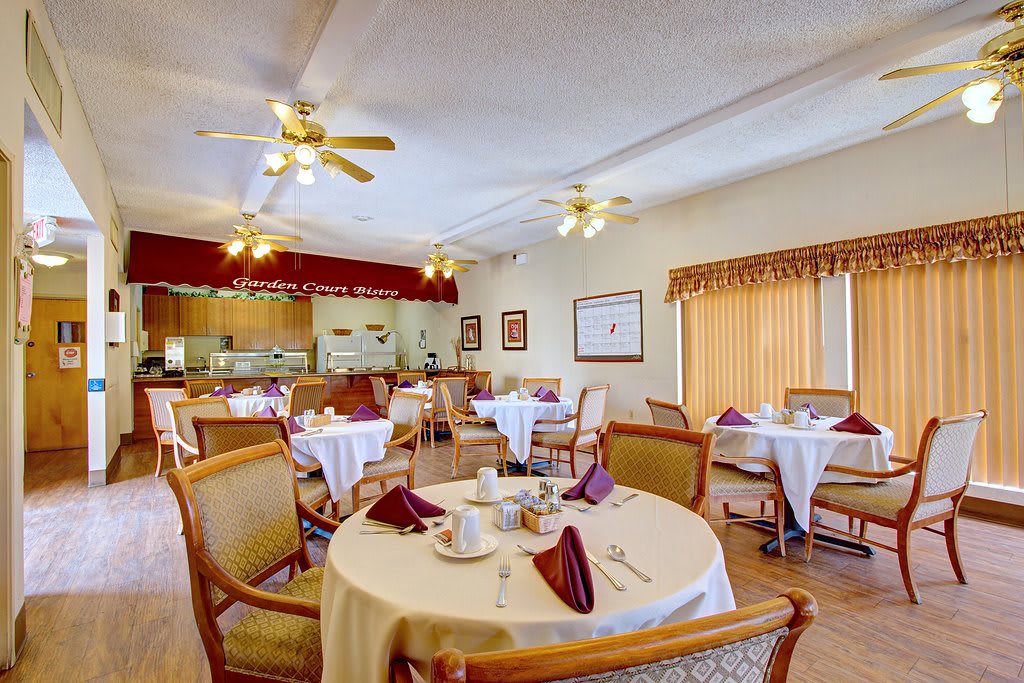 A cozy dining room with elegantly set tables and ceiling fans.