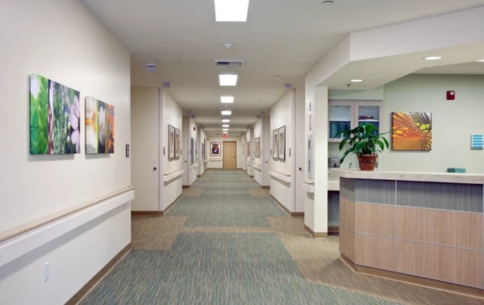 A clean and well-lit hospital corridor with artwork on the walls and a reception desk.