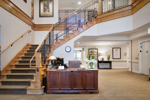 A welcoming lobby with a wooden staircase and reception desk, featuring modern decor and ample lighting.