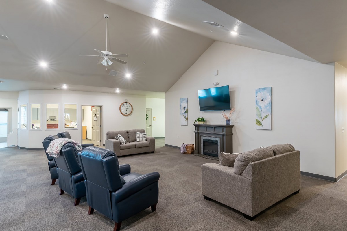A spacious living room featuring comfortable seating, a mounted television, and a modern fireplace.