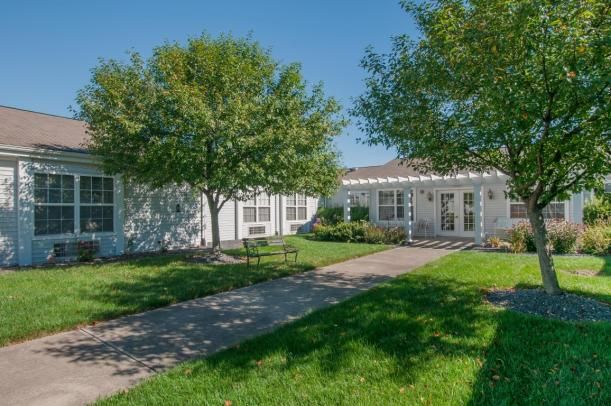 A white residential house with a well-maintained lawn and trees on a sunny day.