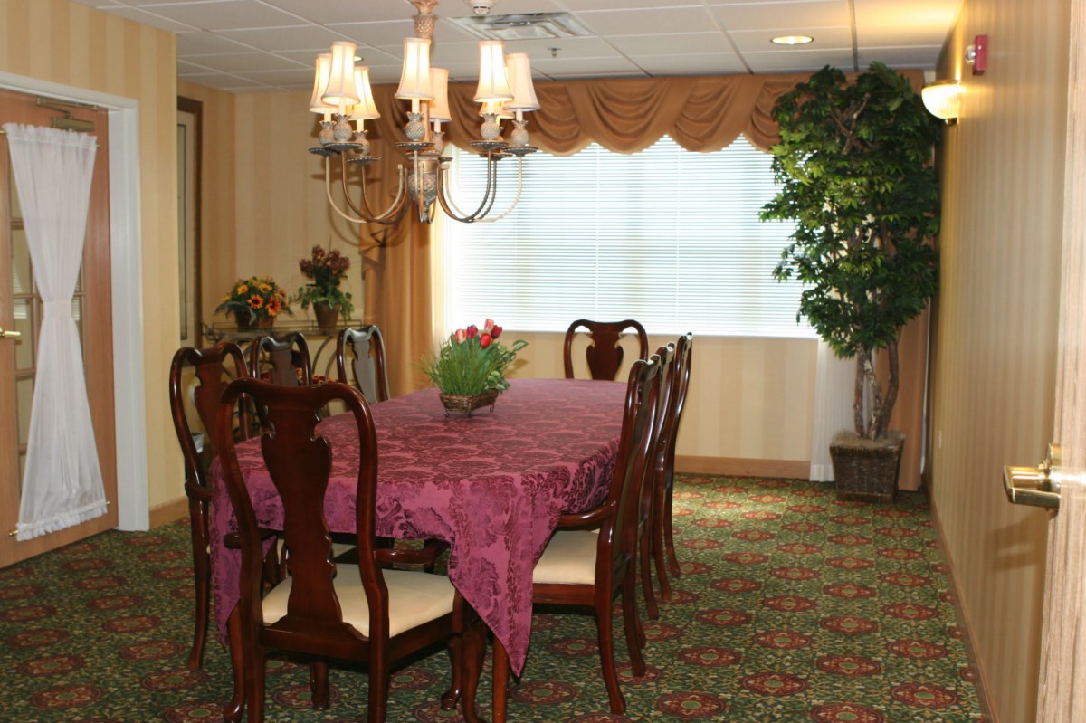 A traditional dining room with a set table and chandelier.
