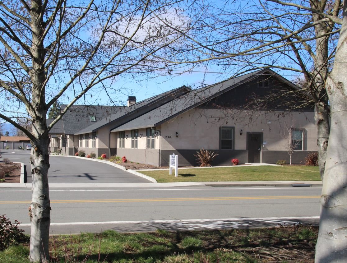A view of residential buildings with a clear blue sky and trees lining the road.