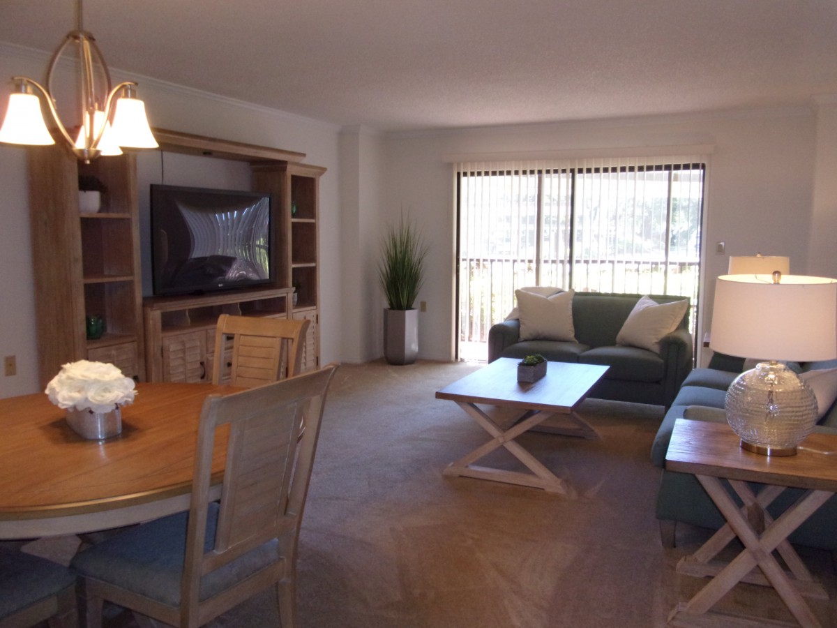 A well-lit living room with a comfortable seating arrangement, dining area, and entertainment center.