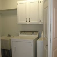 A small laundry room with a washing machine and dryer beneath a set of cabinets.