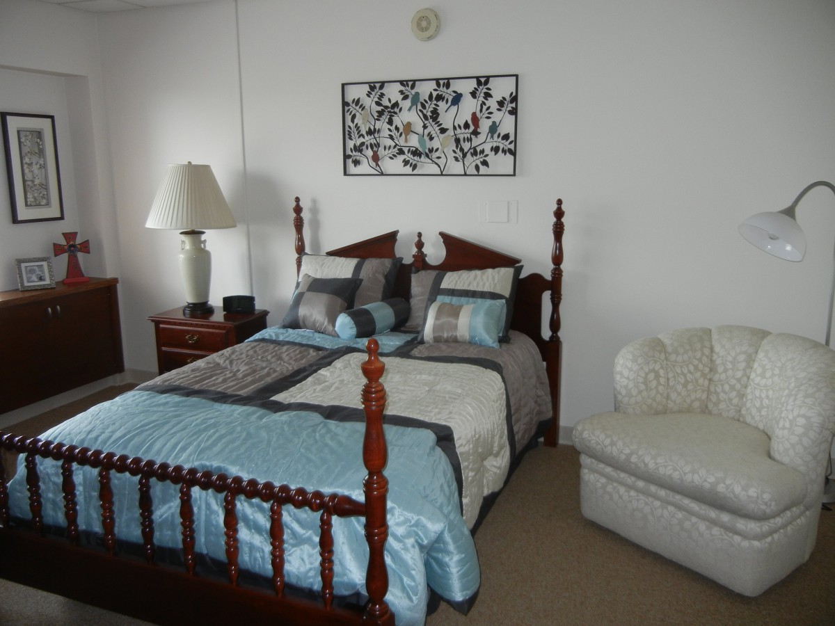 A cozy bedroom with a wooden bedframe, stylish bedding, and a small sofa.