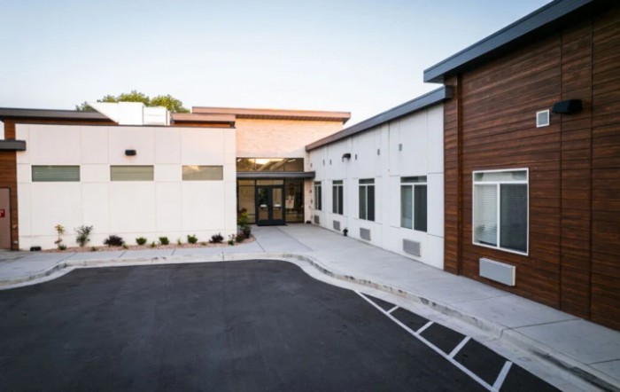 A modern commercial building with a clean driveway leading to the entrance.