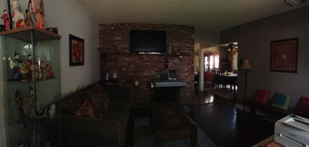 A cozy living room featuring a brick wall with a mounted television and fireplace, complemented by a sofa.